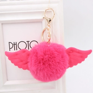 Detail of rose red faux fur pompom keychain with fabric angel wings and gold metal ring