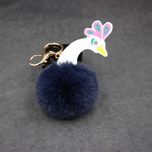 Détail du porte-clés pompon en fausse fourrure de paon avec tête d'oiseau et anneau doré