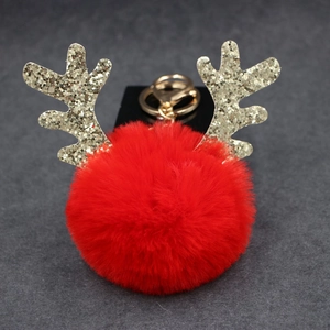 Close-up of red plush reindeer ball keychain with golden sequin antlers and metal clasp