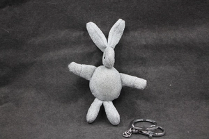 Détail du porte-clés lapin en peluche pailleté argenté avec anneau sur fond de feutre