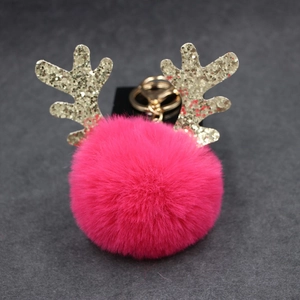 Detail of pink faux fur pompom keychain with golden antlers and metallic ring