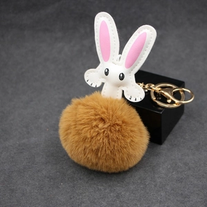 Close-up of brown plush rabbit keychain with white leather head and gold metal ring