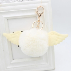 Detail of soft faux fur pompom with angel wings and golden metal lobster clasp