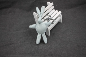 Détail d'un porte-clé lapin en tissu bleu à pois blancs sur un petit banc blanc
