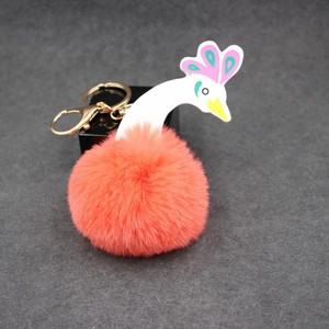 Gros plan d'un porte-clés pompon corail au design de paon créatif avec fermoir en métal doré