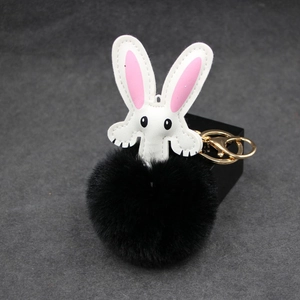 Detail of cute rabbit plush keychain featuring black pompom and gold metal clasp