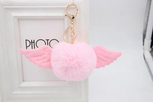 Detailed view of pink faux fur ball keychain with angelic wings and golden hardware