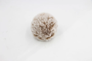Close-up of soft faux fur pompom ball in light brown and cream gradient for bags