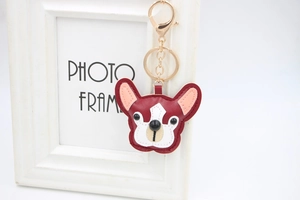 Dettaglio portachiavi a forma di bulldog in pelle PU bordeaux e bianca con gancio d'oro