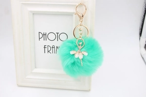 Detailed close-up of a mint green faux fur ball keychain with a ballet dancer pendant