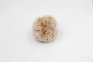 Close-up of a soft khaki faux fur pom-pom with dense texture and fluffy design