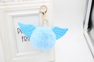 Detail of blue faux fur pompom keychain featuring angel wings and gold spring ring
