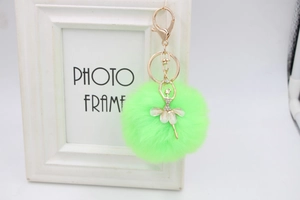 Detail of neon green plush pompom keychain with golden ballerina charm and rhinestones
