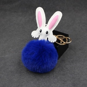 Detailed view of royal blue faux fur rabbit keychain with gold hardware and white leather