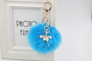 Detail of blue faux fur pompom keychain with golden ballerina pendant and rhinestones