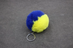 Détail du pompon bicolore bleu et jaune en fausse fourrure avec porte-clés en métal