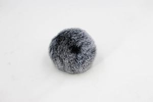 Close-up of fluffy gray and black faux rabbit fur pom pom for bags and hats accessory
