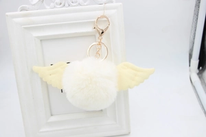 Close-up of white plush ball keychain with angel wings and golden metal lobster clasp