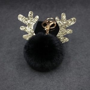 Close-up of black fluffy pom pom keychain with sparkling golden sequin reindeer antlers