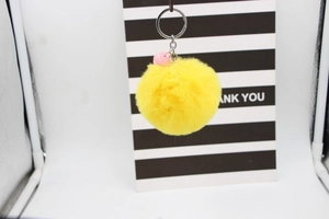 Close-up of bright yellow plush faux fur keychain with silver ring and small pink bell