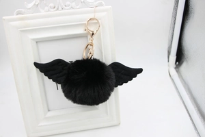 Detail view of a fluffy black angel wing pompom keychain with golden metal ring and chain