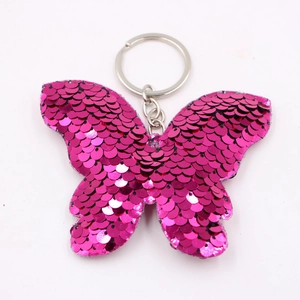 Portachiavi a farfalla con paillettes rosso rosa e anello in metallo su sfondo bianco