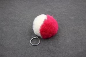 Détail d'un porte-clés pompon bicolore en fausse fourrure de lapin blanc et rose vif