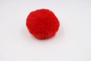 Close-up detail of a bright red 8cm faux rabbit fur pom pom with soft plush texture