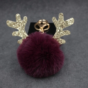 Close-up of a purple reindeer pompom keychain with gold glitter antlers and clasp