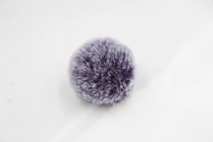 Detailed view of bicolor purple and white faux fur pom pom with fluffy texture
