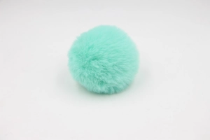 Close-up of mint green fluffy pom-pom with soft faux rabbit fur texture for accessories