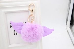 Close-up of lavender faux fur pom pom keychain with purple angel wings and gold clasp
