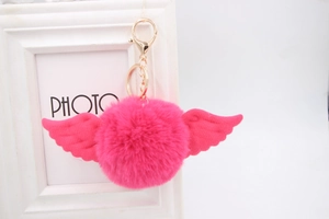 Detail of rose red fluffy pompom keychain with white angel wings on gold metal ring