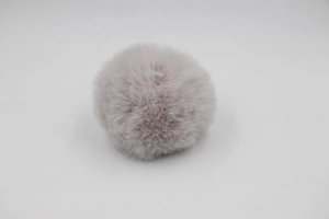 Detail of a dusty pink faux fur pompom with fluffy texture for bags and DIY crafts