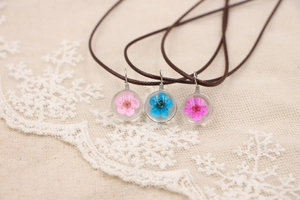 Détail macro de pendentifs fleurs séchées faits main dans des sphères en verre clair