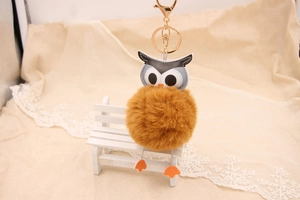 Détail d'un porte-clés hibou en fausse fourrure avec pompon doux sur un petit banc