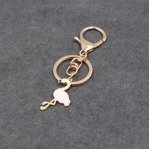 Nahaufnahme vom goldfarbenen Metall-Schlüsselanhänger mit rosa Emaille-Flamingo-Anhänger