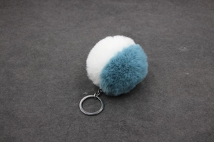 Détail d'un porte-clés bicolore en fausse fourrure blanche et bleu sarcelle avec anneau
