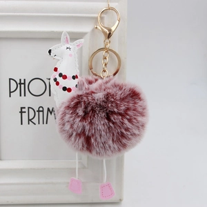 Dettaglio di un portachiavi a forma di alpaca bianco con un grande pompon di pelliccia bordeaux