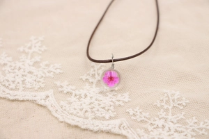 Détail de la fleur de cerisier rose faite main dans un pendentif en verre transparent