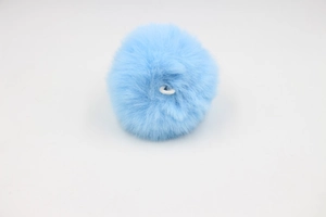 Detail of light blue faux fur pompom with white elastic loop for bag accessories
