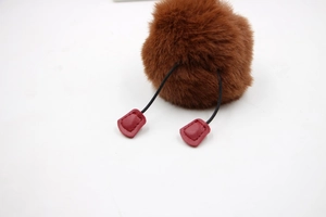 Detail of plush brown faux fur ball pendant with leather accent and black elastic cords