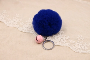 Close-up of a fluffy dark blue faux rabbit fur pompom keychain with a pink bell
