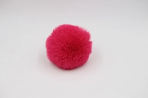 Detailed view of a fluffy rose red synthetic pom-pom ball for bags and accessories