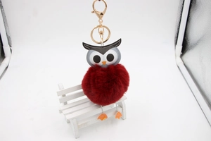 Détail d'un porte-clés hibou avec pompon rouge moelleux et fermoir mousqueton doré