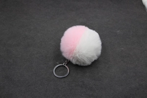 Détail du porte-clés pompon bicolore en fausse fourrure rose et blanc avec clip métal