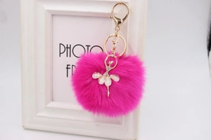 Detailed close-up of rose red faux fur pom-pom keychain with golden ballerina charm