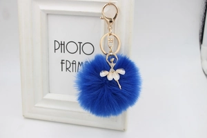 Close-up of royal blue plush fur pompom keychain with a sparkling ballerina charm