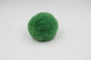 Macro shot of fluffy grass green faux rabbit fur pom-pom ball for bags and accessories