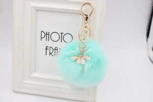 Close-up of mint green faux fur ball keychain with rhinestone ballet dancer pendant